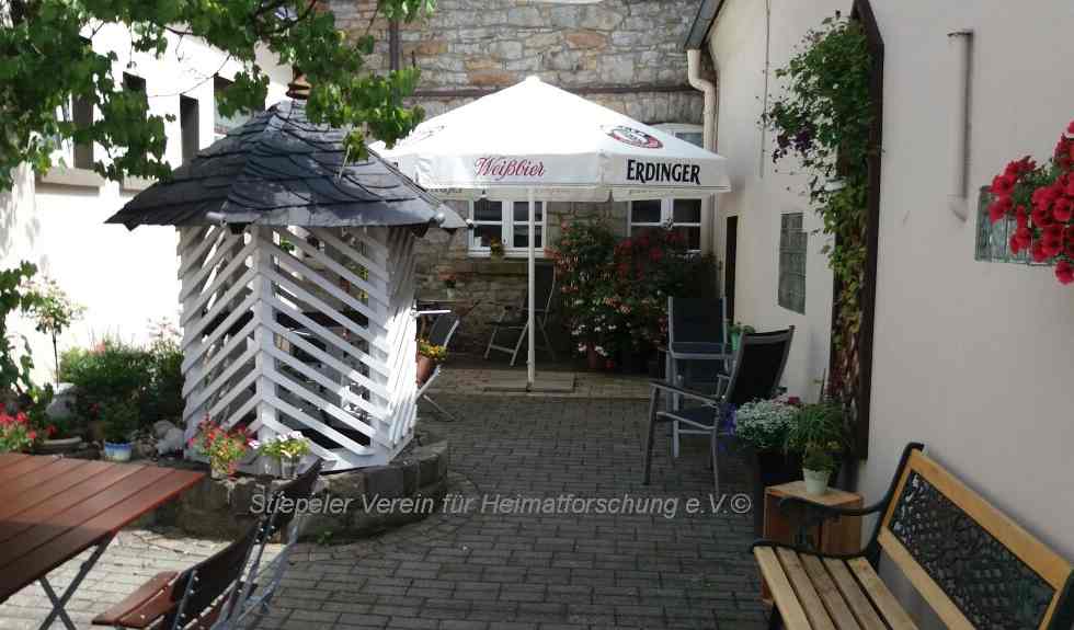 Der Innenhof mit der in Ruhrsandstein gemauerten Wand, Biergarten und Brunnen