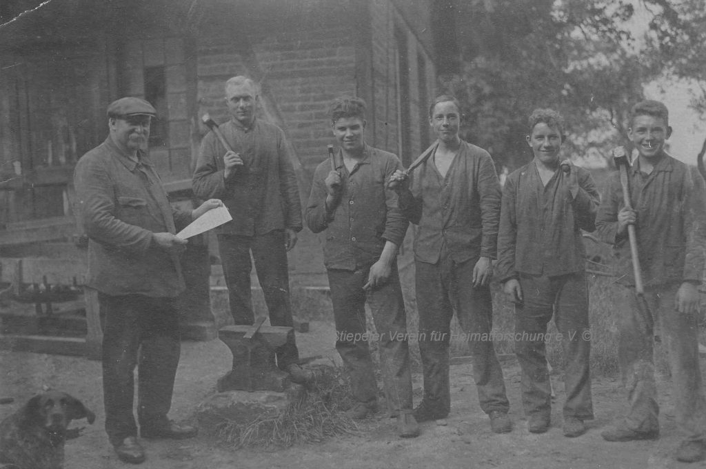Vater und Sohn Gathmann mit Gesellen vor der Schmiede, 1920er Jahre